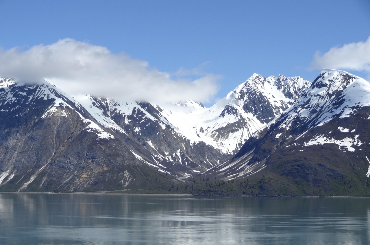 Snowcapped Alaska mountains reflected in calm fjord water