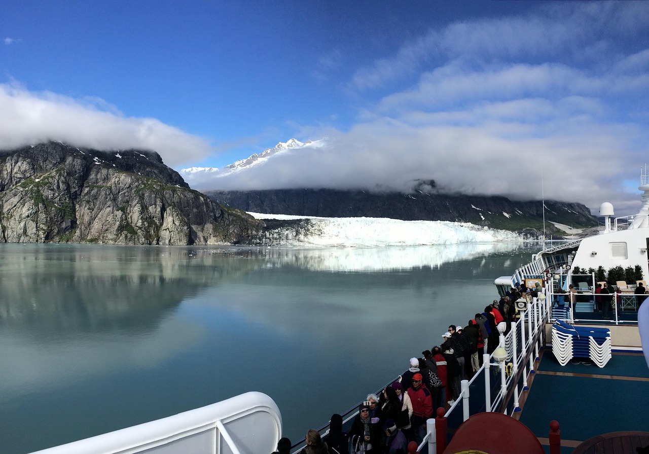 Cruise ship passengers watching a tidewater glacier in Alaska under snowcapped mountains