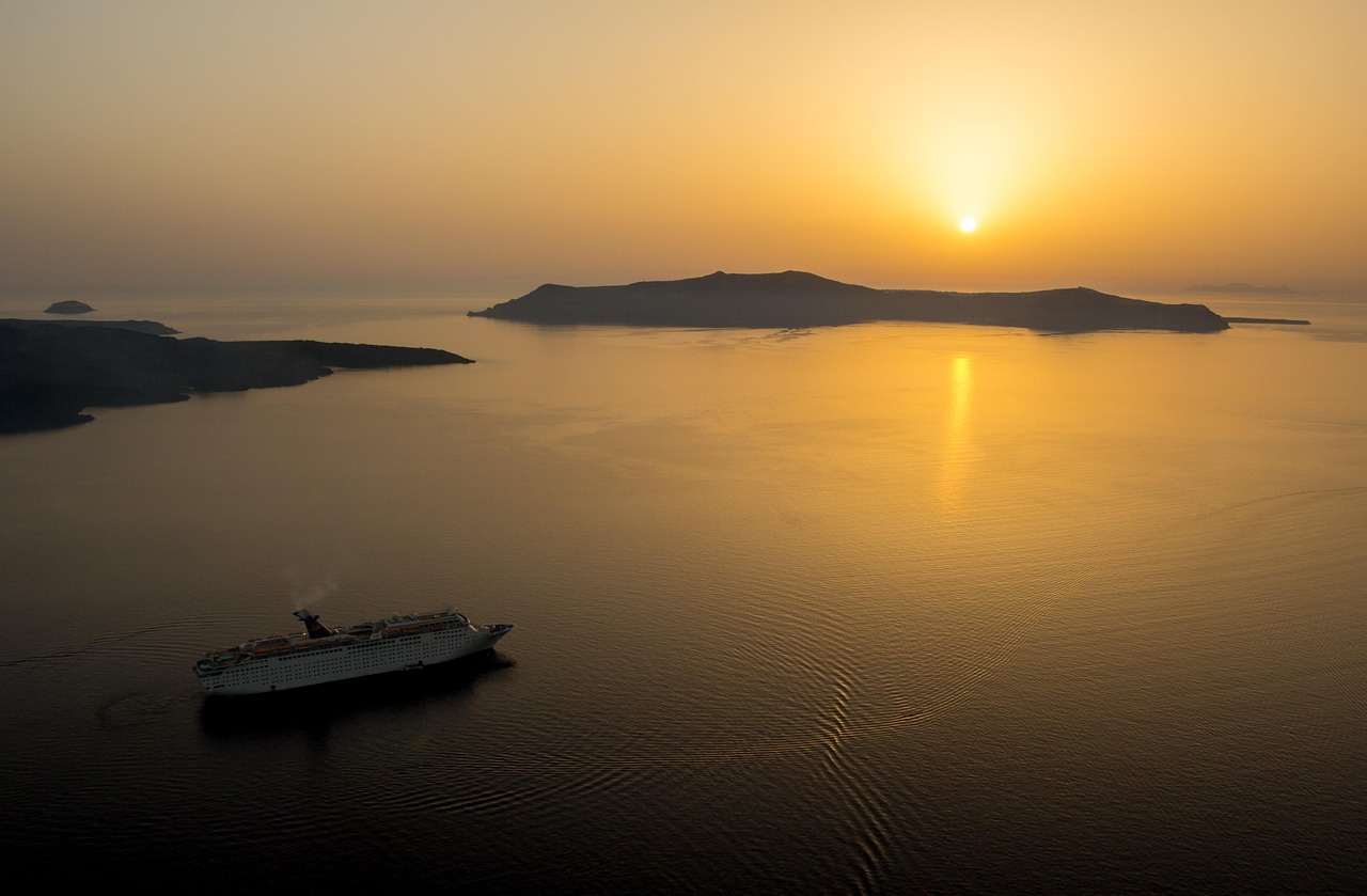 A cruise ship sailing at sunset near Santorini, Greece