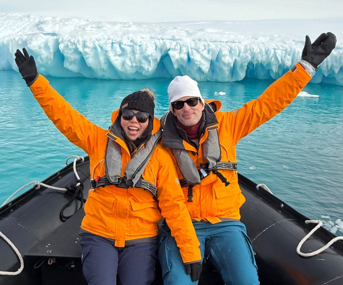 Renee Raver cheering in a Zodiac boat beside an iceberg in Antarctica
