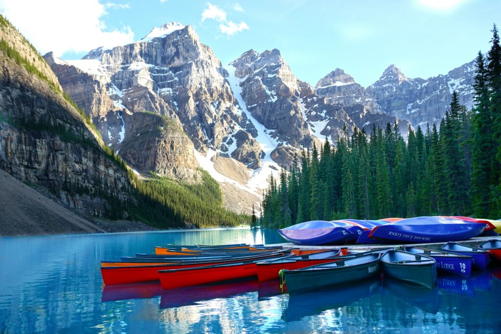Canoes lined up on a dock in Banff National Park with snow-capped mountains in the distance
