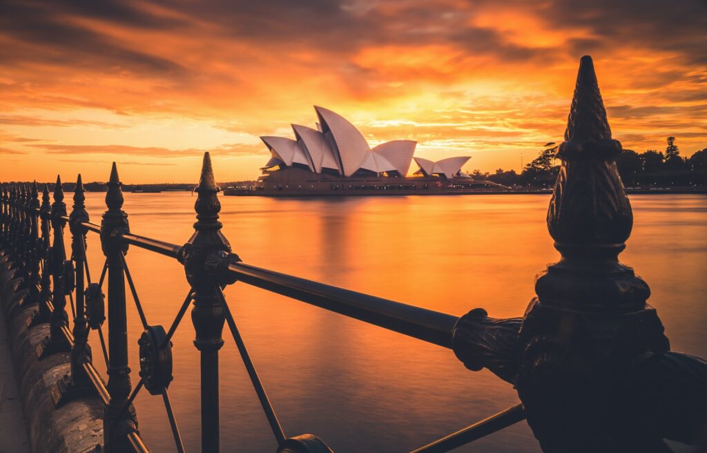 the sydney operhouse from a bridge across the water during an orange sunset