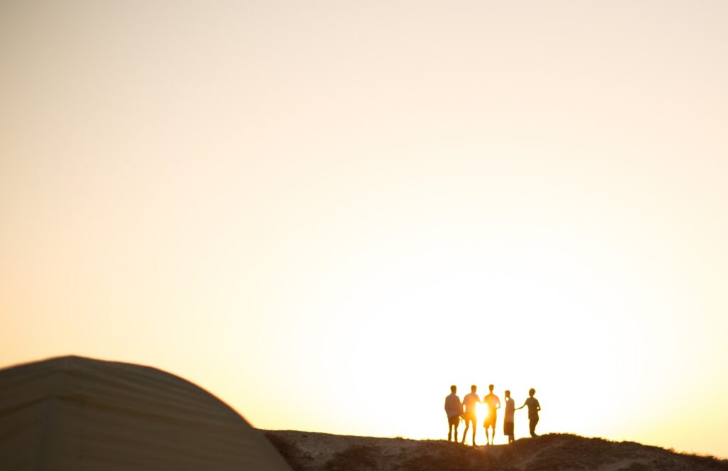 a group of five men stand looking at a sunset travel agent
