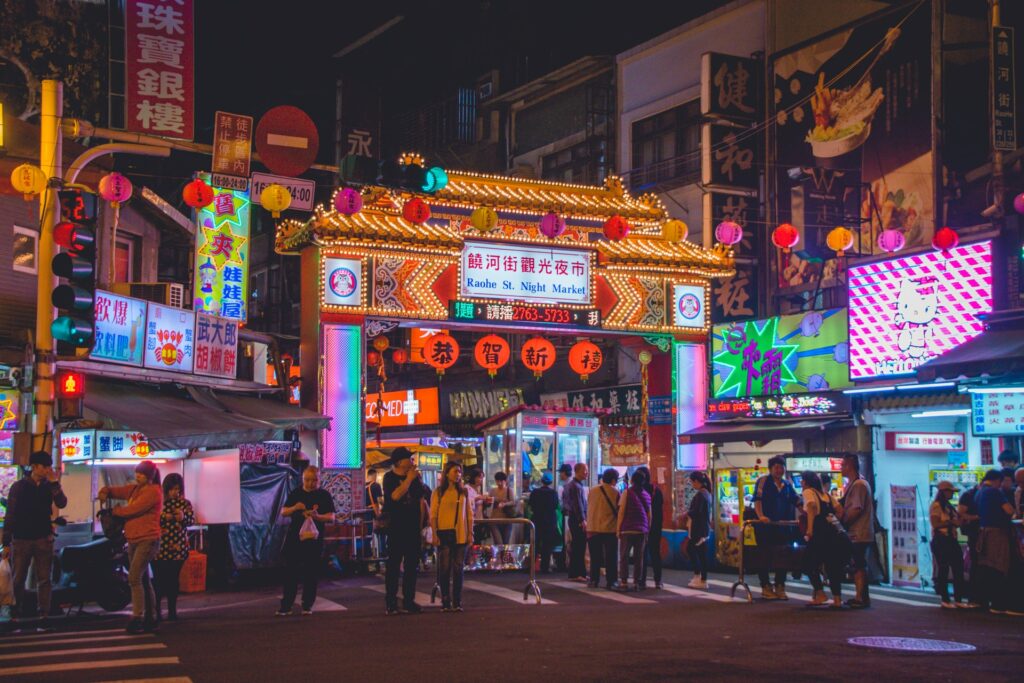 tourists stand outside the raohe street night market in Taipei, Taiwan