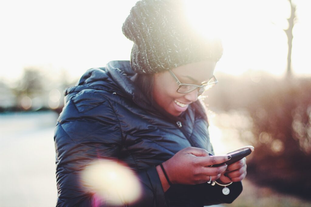 travel tip #3: stay connected. A woman looks at her cell phone while smiling