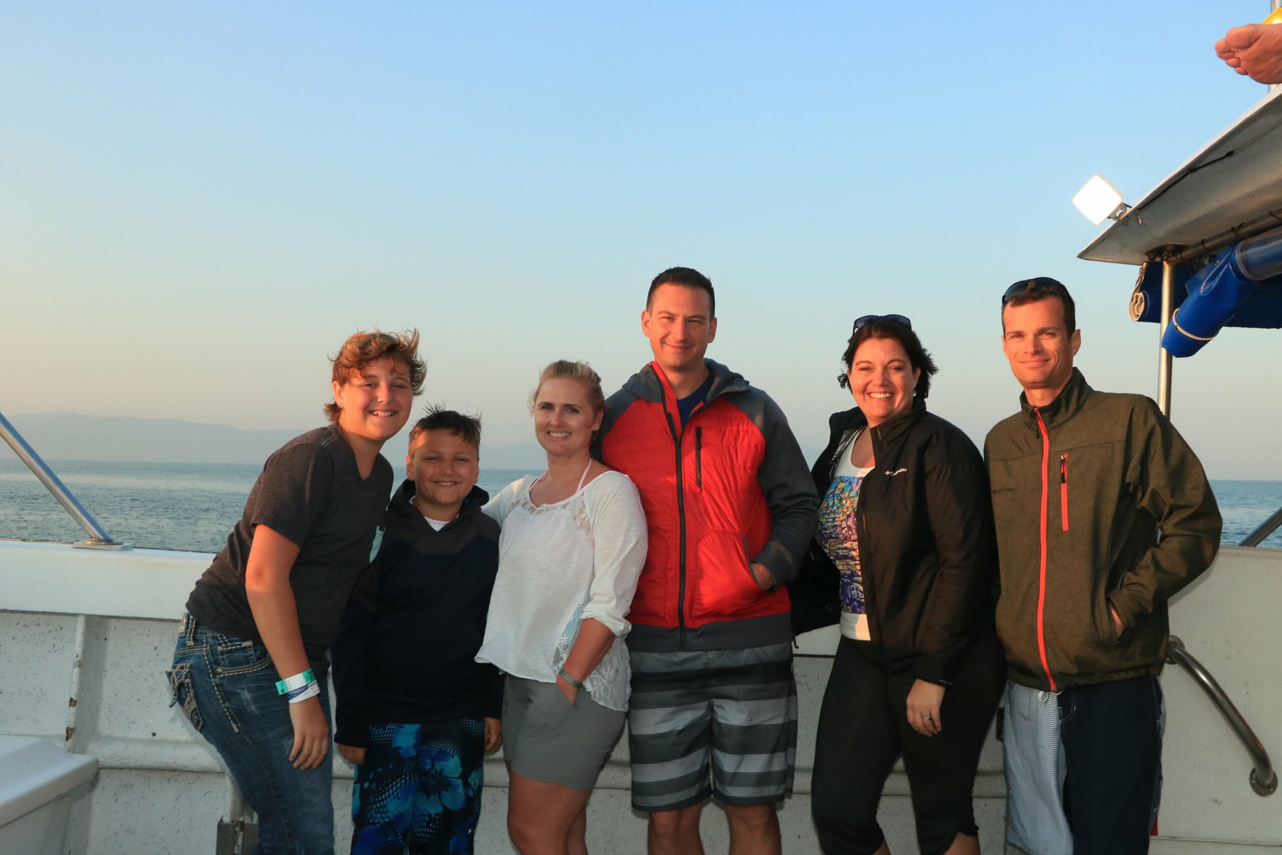 Awaken travels agent cindi sanden stands on a boat with her family and friends in Mexico