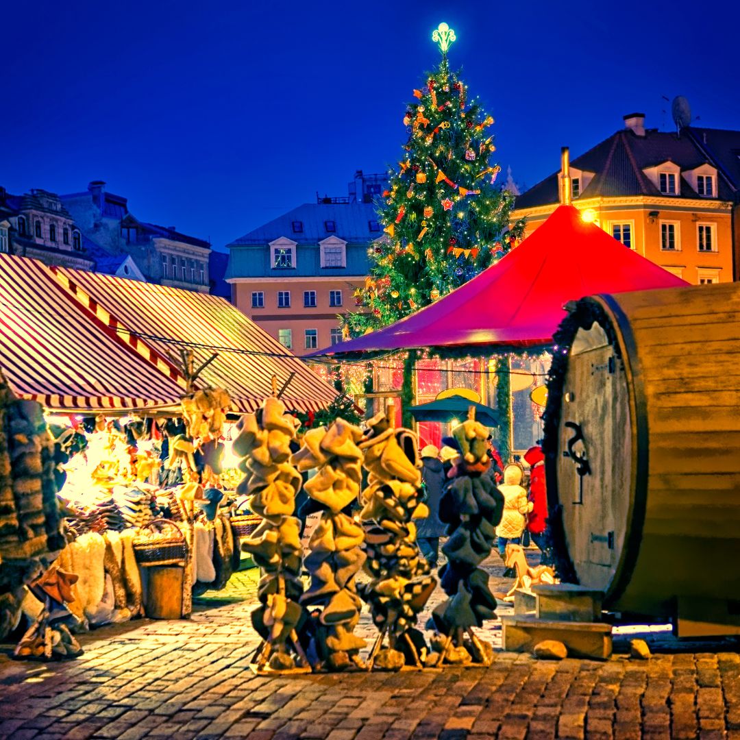 Vibrant Christmas market with festive tree and wooden chalets at twilight.