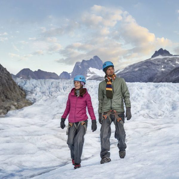 Adventurous couple hiking on a glacier during a Norwegian Cruise Line Alaskan excursion.