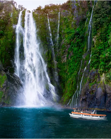 Swan Hellenic cruise ship on a majestic voyage, passing by a towering, multi-stream waterfall cascading into a serene blue sea.